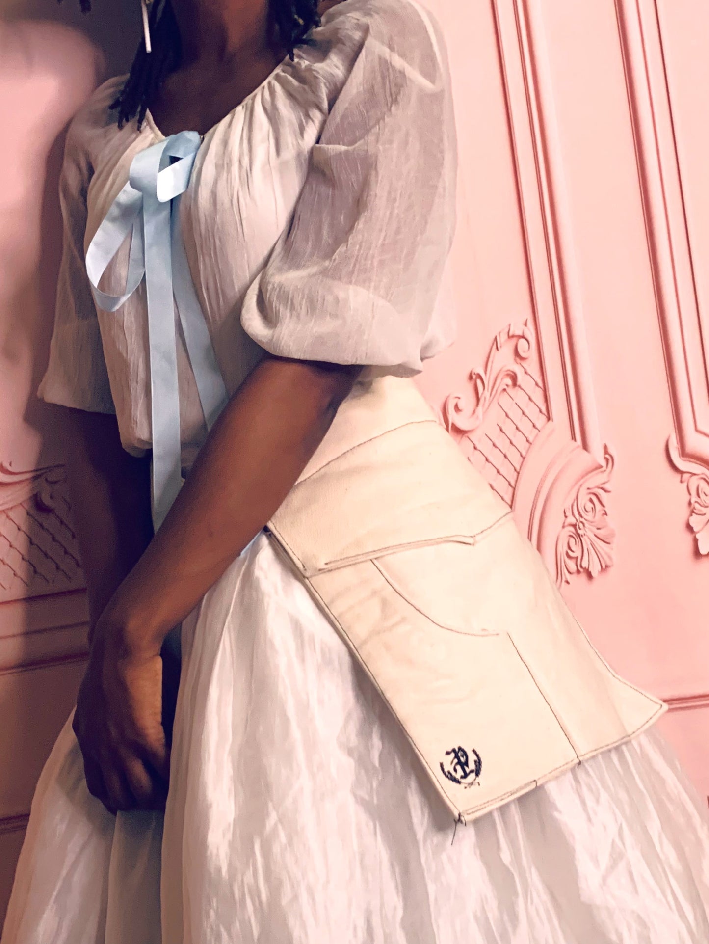 A young woman wearing a pair of off-white pockets  in frint of a regal pink background